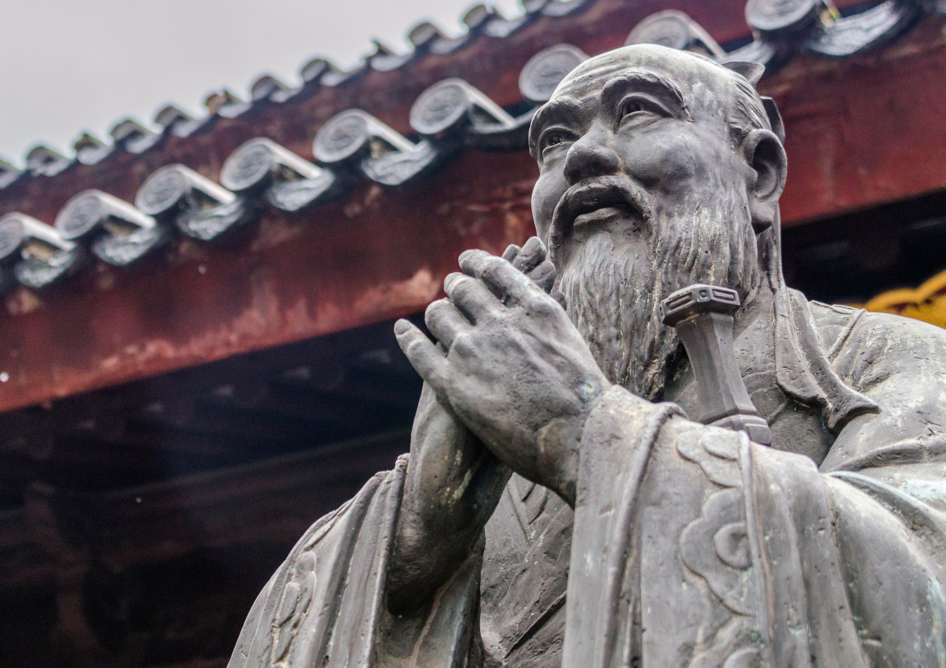 Escultura de un filósofo chino con gesto de oración, símbolo del confucianismo y la sabiduría ancestral.